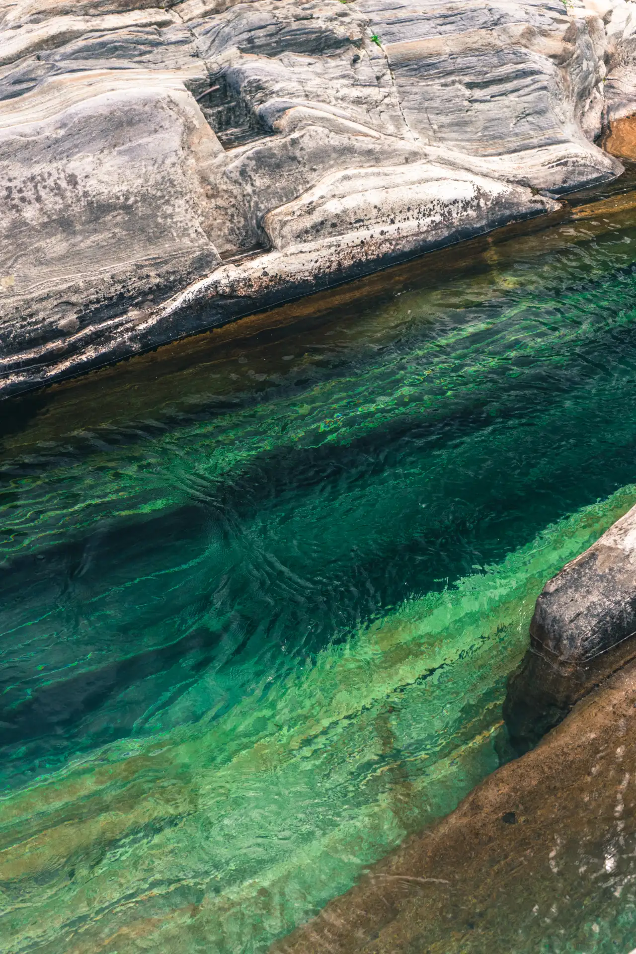 rio cristalino próximo a uma pedra cinza